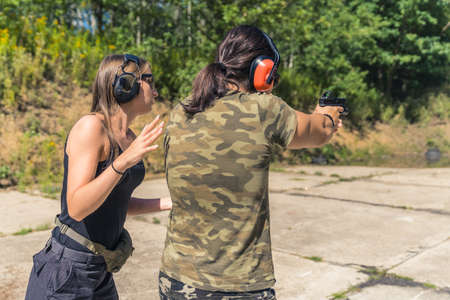 Two Europeans at a shooting range. Private shooting lessons. Female instructor and a man in moro...