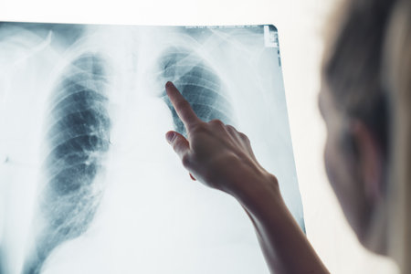 Unrecognisable blonde female doctor pointing at x-ray of patients lungs. Close up. Studio shot....
