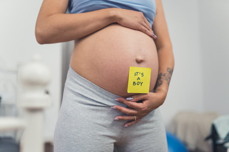 pregnant womans belly with a sticky note saying boy, closeup gender reveal concept. High quality photoの写真素材