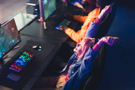 Female asian woman in her 20s pressing buttons on a lighted colorful keyboard and mouse, cheering after a phenomenal win in a video game. High quality photoの写真素材