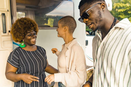 A multicultural group of college friends standing near their motorhome and talking, laughing, enjoying spending time together camping in nature . High quality photoの写真素材