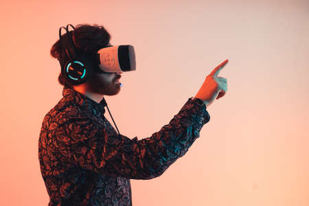 Side view of a man using the virtual touch operations with vr goggles on his head - studio medium shot. High quality photoの写真素材