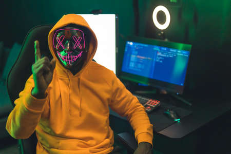 Black man wearing a dark mask with pink patterns covering his face, pointing his finger at the...