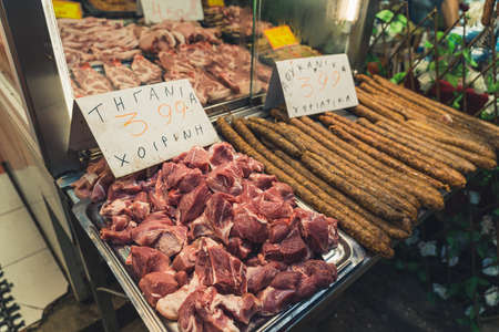 Greek butchers shop at Kapani Market. Fresh juicy meat and long sausages placed on metal trays. Meat...