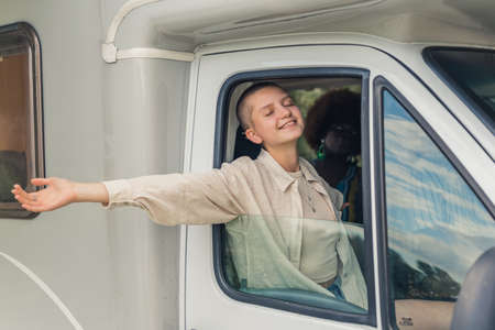 young joyful woman in the van enjoying the fresh air, medium shot. High quality photoの写真素材