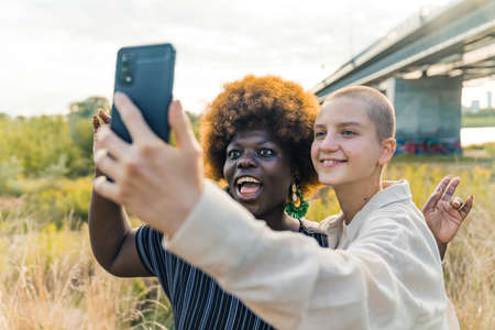 multiracial women taking a funny photo together, medium closeup outdoors. High quality photoの写真素材