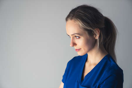 A young, confident, trustworthy female doctor standing over an isolated white background looking away to the side with a smile on her face, a natural expression. High-quality photoの写真素材
