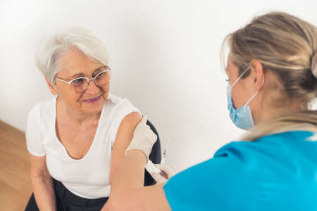 A senior woman smiling and looking happy after getting vaccinated by a healthcare nurse. High quality photoの写真素材