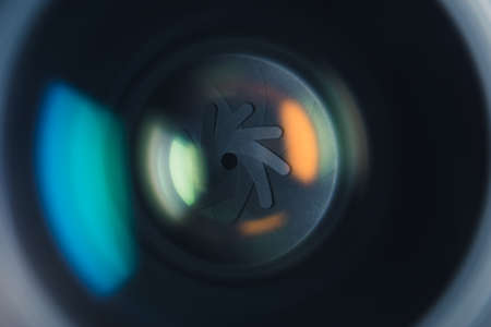 Close-up professional camera lens with color reflections. Aperture blades opening and closing during shooting. High quality photoの写真素材