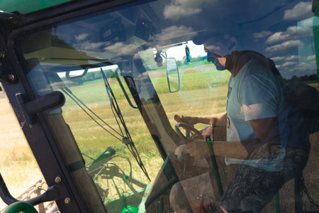 07.28.2022 Warsaw, Poland. Caucasian middle-aged farmer and combine harvesters operator sitting behind the wheel and harvesting rapeseed crops. Focus during work. High quality photoのeditorial素材