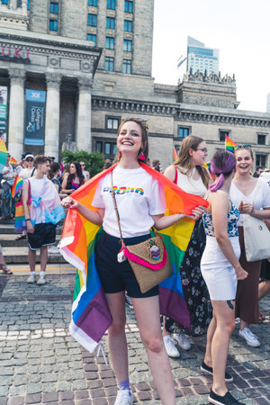 June 25, 2022 Warsaw, Poland - Ukraines KyivPride teams up with Polands Warsaw Pride to march for peace and equal rights. A girl wrapped in LGBTQ flag and smiling to the camera. High quality photoのeditorial素材