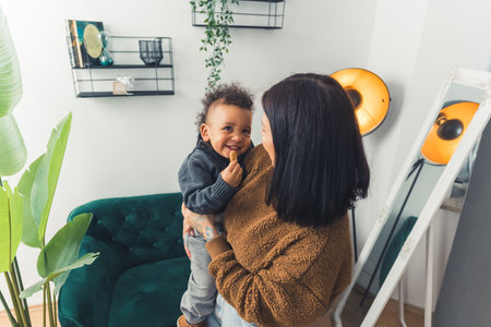 Young and energetic caucasian mother spending her time with her African origin baby boy in a room - room atmosphere background. High quality photoの写真素材