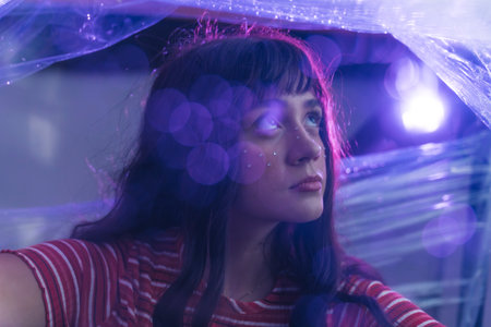charming European girl surrounded by the cellophane looking up confidently, closeup shot blurred...