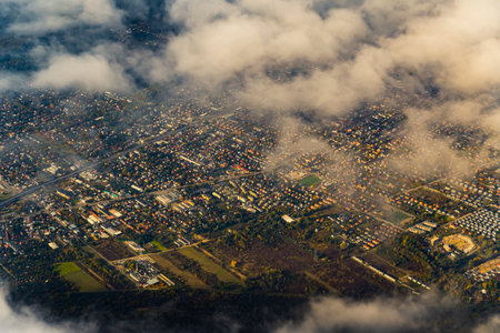 Aerial perspective of the city of Warsaw - capital city of Poland. View from plane window. Autumn morning with soft sunshine and fluffy clouds. High quality photoの写真素材