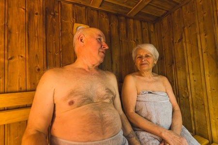 Idea for a gift for grandparents. Sauna and SPA day. Indoor medium closeup shot of two caucasian senior adults sitting together in a sauna,. High quality photoの写真素材