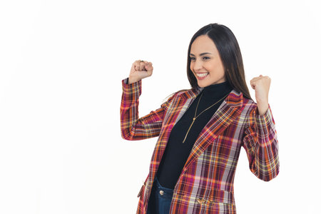 young cheerful woman celebrating her success by holding her fists up, medium shot copy space...