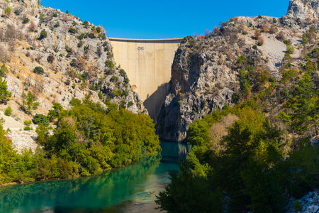 10.13.2022 - Manavgat, Turkey - Olympinar Lake Dam with rocky mountains bushes and trees in the morning sun. Clear blue water lake. Horizontal outdoor shot. High quality photoのeditorial素材