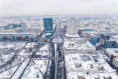 11.21.2022 Warsaw, Poland. Dmowski Roundabout in the centre of Warsaw. Streets of European capital city covered with snow. Cloudy sky. High quality photoのeditorial素材