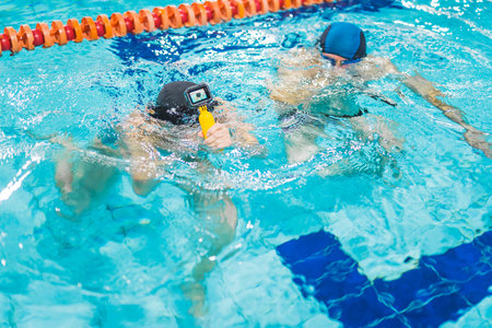 Friendly breath-holding competition. Two unrecognizable people holding breath and submerging under...