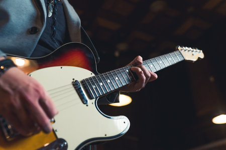Guitarist and guitar. Closeup indoor shot of unrecognizable caucasian man playing with his hands on an electric guitar. High quality photoの写真素材