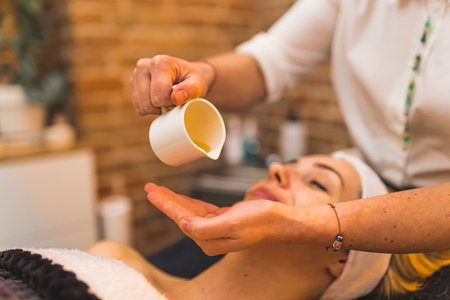 A beautician applying oil for facial skin massage for a woman. High quality photoの写真素材