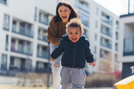 Young, grinning, Caucasian mother chasing her interracial toddler - motherhood and parenting. High quality photoの写真素材