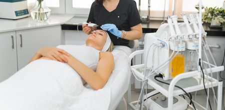 Medium shot of a beautician doing microdermabrasion treatment on a woman. Beauty concept. High...