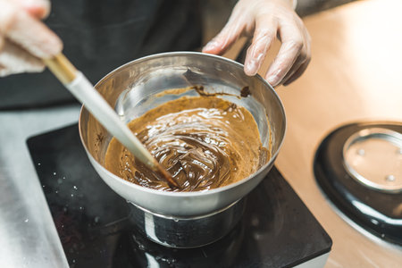 Melting chocolate in a metal bowl. High angle view. Closeup shot. Baker or chef whisking melted chocolate in a bowl with spatula. High quality photoの写真素材