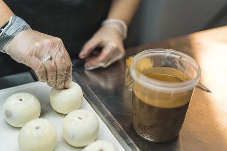 Baker is getting ready to put a round white cake into caramel icing. Medium close up. High quality photoの写真素材