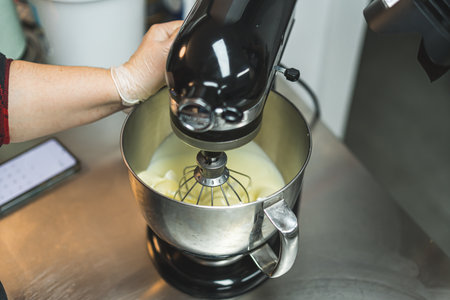 Closeup portrait of a food processor in use. Standing mixer mixing vanilla buttercream frosting....