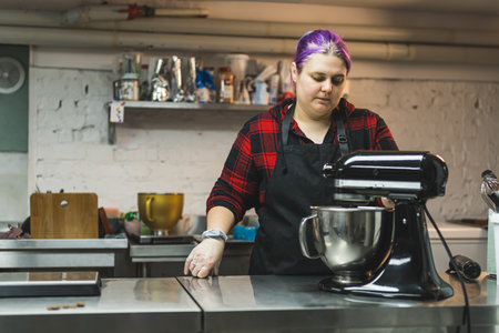 female baker with purple hair mixing products in a bowl at the kitchen, bakery, cooking concept....
