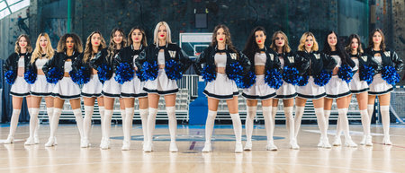 Confident cheerleaders posing in mini-skirts holding pompoms showing team spirit. High-quality photoの写真素材