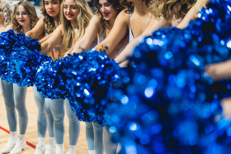 Medium shot of a group of cheerleaders with their arm stretched. Blurred foreground. Sport concept. High quality photoの写真素材