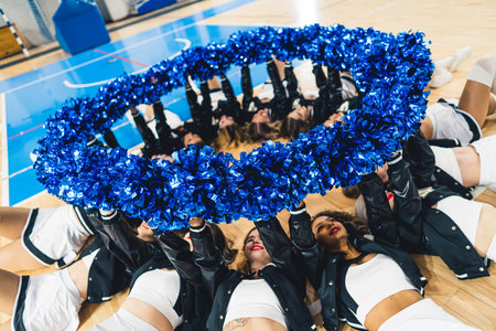 Cheerleaders laying on basketball court holding their blue shiny pom-poms up in a circle. High quality photoの写真素材