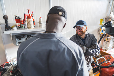 Professional auto repair mechanics in uniform at work in a busy car repair shop. High-quality photoの写真素材