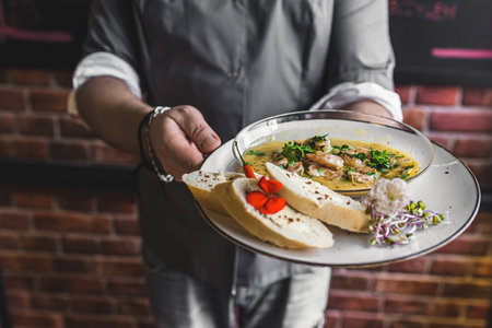 Unrecognisable waiter serving spicy chilli sauce shrimp dish with buttered bread. Restaurant service. Horizontal indoor shot. High quality photoの写真素材