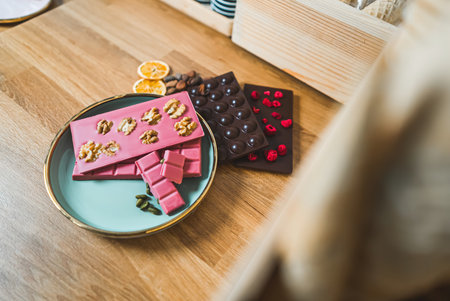 Bean-to-bar craft dark and pink chocolate bars with dried fruits and nuts on the table. High quality...