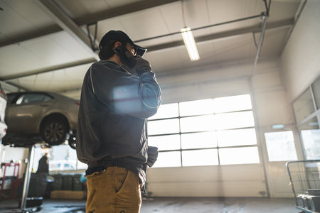 Low angle shot of a mechanic talking on the phone in a repair shop. High quality photoの写真素材
