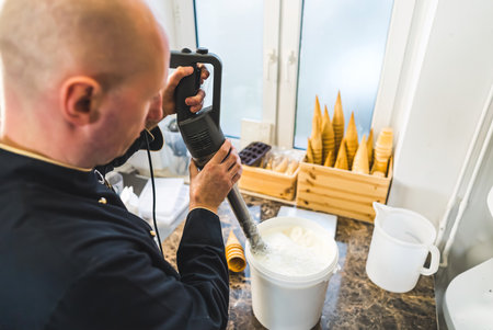 Back top view of man chef mixing milk with professional blender for ice cream production in the kitchen. High quality photoの写真素材