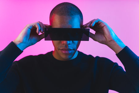 Front view of a man wearing VR goggles on pink studio background . High quality photoの写真素材