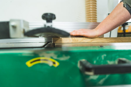 Closeup shot of carpenters hand holding wooden plank on professional carpentry machine. Tools used in woodworking. High quality photoの写真素材
