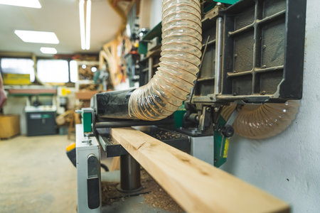 Wooden desk placed on sawdust extractor machine table in carpentry workshop. No people. High quality photoの写真素材
