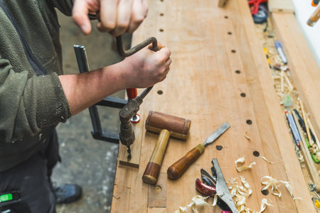 Carpenter using brace. Adult male woodworking expert using manual drill to create a hole in a piece of wood. High angle view. High quality photoの写真素材