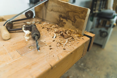 Brace - old woodworking tool instead of automatic drilling machine - placed on wooden table next to wood filings. No people. Copy space. High quality photoの写真素材