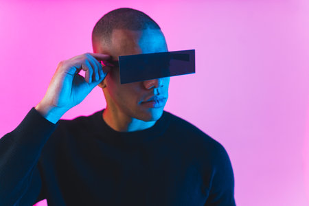 handsome Afro man with black square-shaped modern sunglasses posing on pink background, medium closeup. High quality photoの写真素材