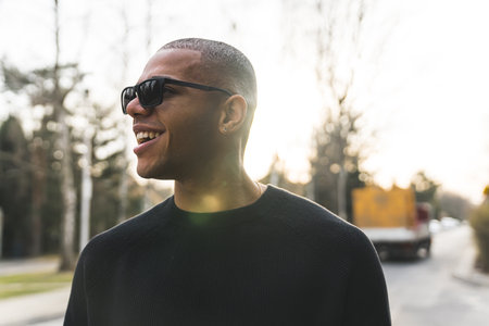 Smiling African American man in sunglasses standing outside in the sun. High quality photoの写真素材