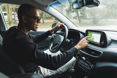 Young man in a car driver seat tapping with finger on multimedia screen . High quality photo