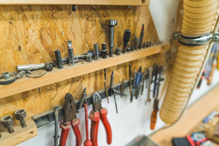 Variety of different tools such as standard pliers, screwdriver, and nails hanging on a wall....