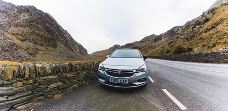 02.28.2023 - Snowdonia, Wales. A front view of a car parked on a road leading through the mountain national park. High quality photoのeditorial素材