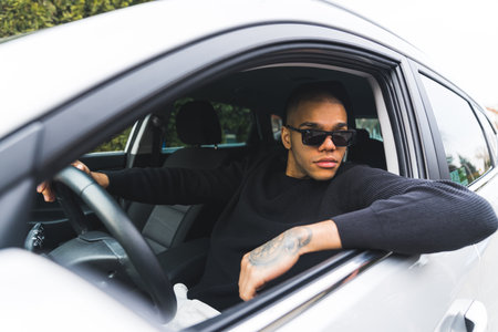 African American man in sunglasses leaning out of a car window and looking away. High quality photoの写真素材